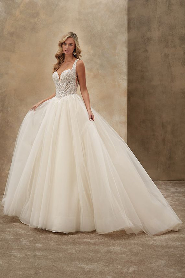 Eine blonde Frau lächelt und trägt ein weißes glamouröses Brautkleid mit Tüllrock