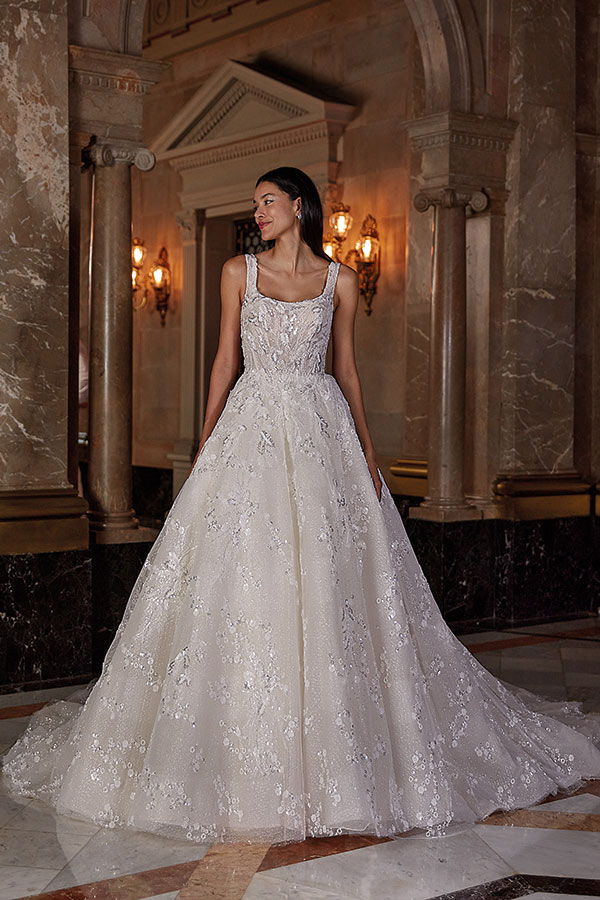 Eine Frau mit glücklichem Ausdruck trägt ein elegantes weißes Spitzenkleid im Ballsaal