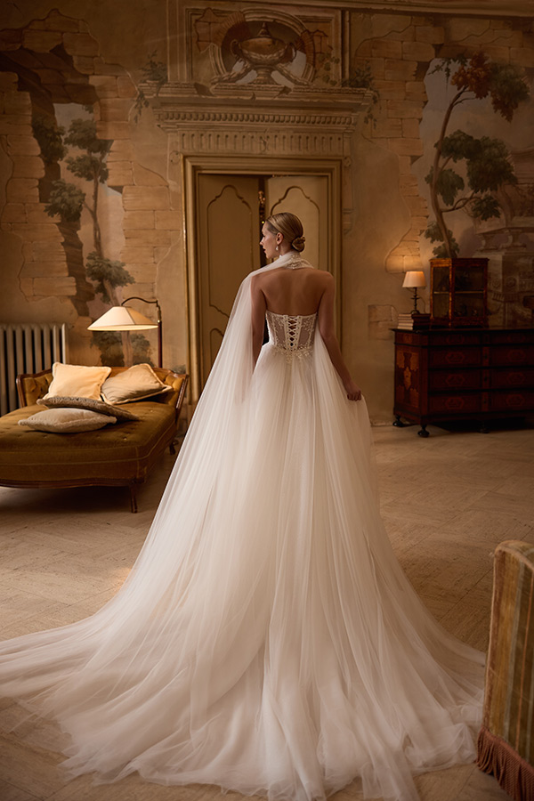 Eine elegante Frau im weißen Brautkleid mit langer Schleppe steht in edlem Raum