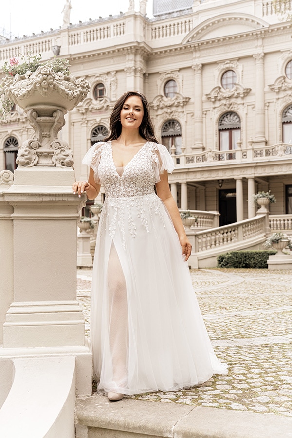 Lächelnde Frau im weißen Spitzenkleid steht vor einem prächtigen historischen Gebäude