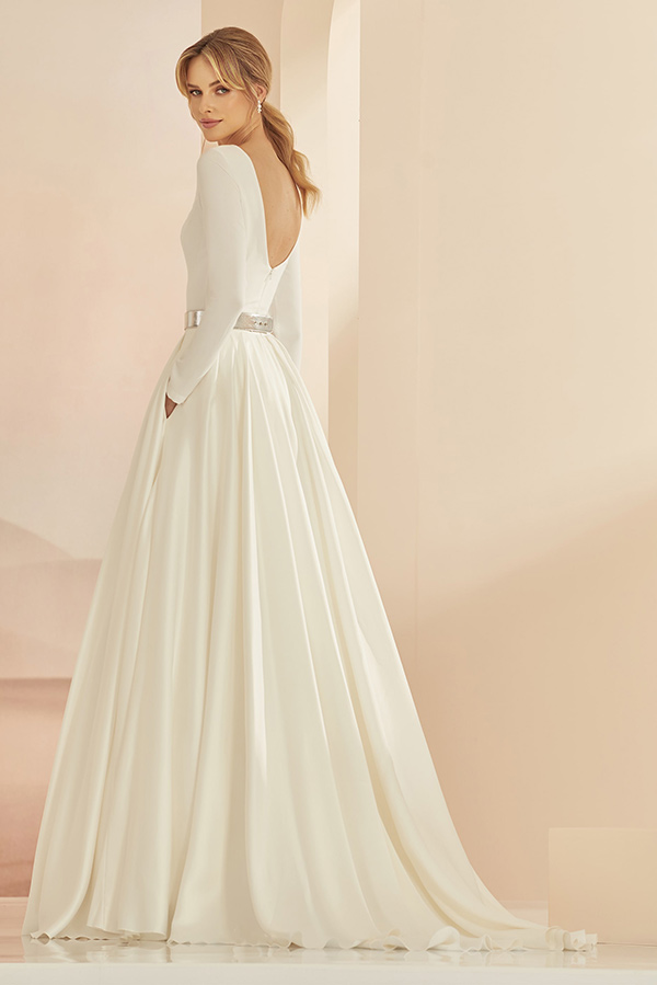 Junge Frau mit elegantem Ausdruck trägt cremeweißes Kleid mit tiefem Rückenausschnitt