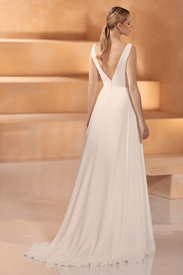 Eine blonde Frau im eleganten weißen Kleid mit tiefem Rückenausschnitt und Pferdeschwanz