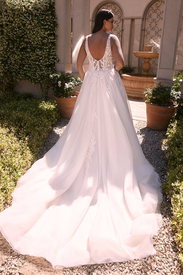 Eine Frau mit langen dunklen Haaren trägt ein weißes Brautkleid mit Spitze und Schleppe