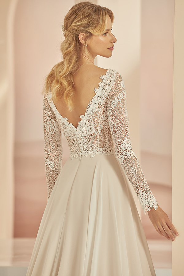 Eine blonde Frau mit lockerem Haar trägt ein elegantes cremefarbenes Spitzenkleid