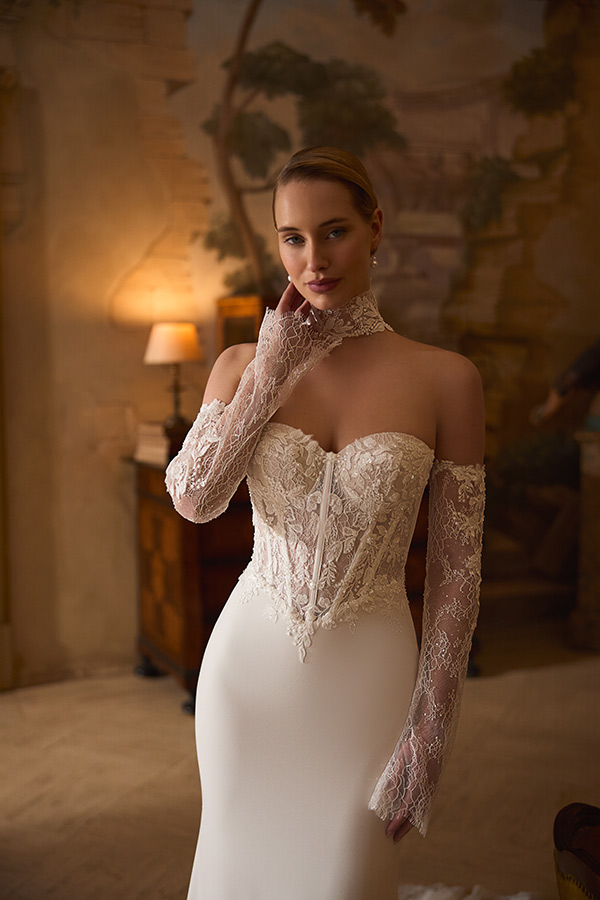 Eine junge Frau mit sanftem Lächeln trägt ein elegantes weißes Spitzenkleid