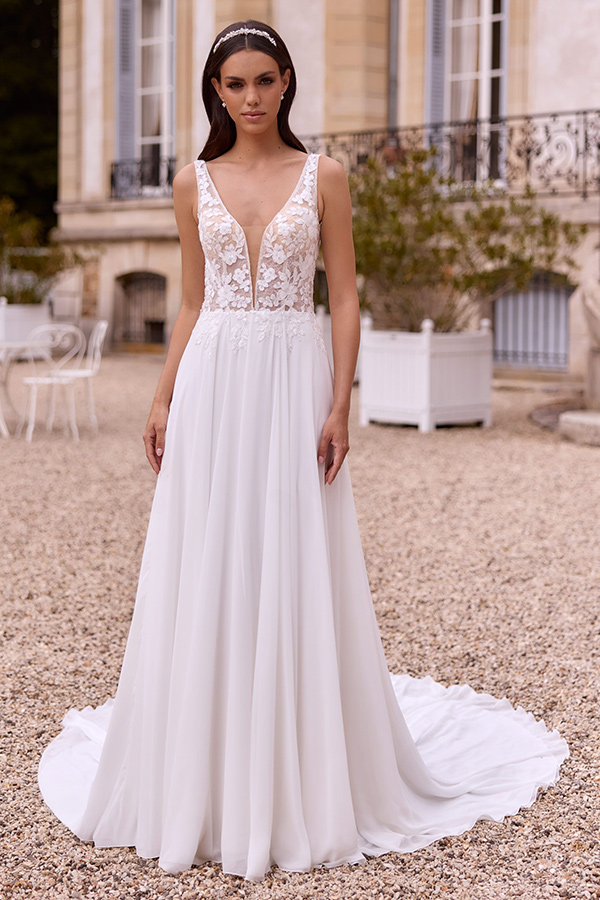 Braunhaarige Frau im weißen Brautkleid mit Spitzenoberteil steht entspannt draußen