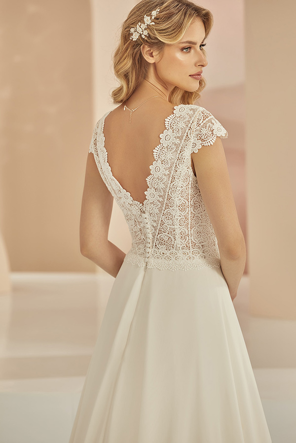 Eine blonde Frau schaut nach hinten und trägt ein elegantes Spitzenkleid in Creme