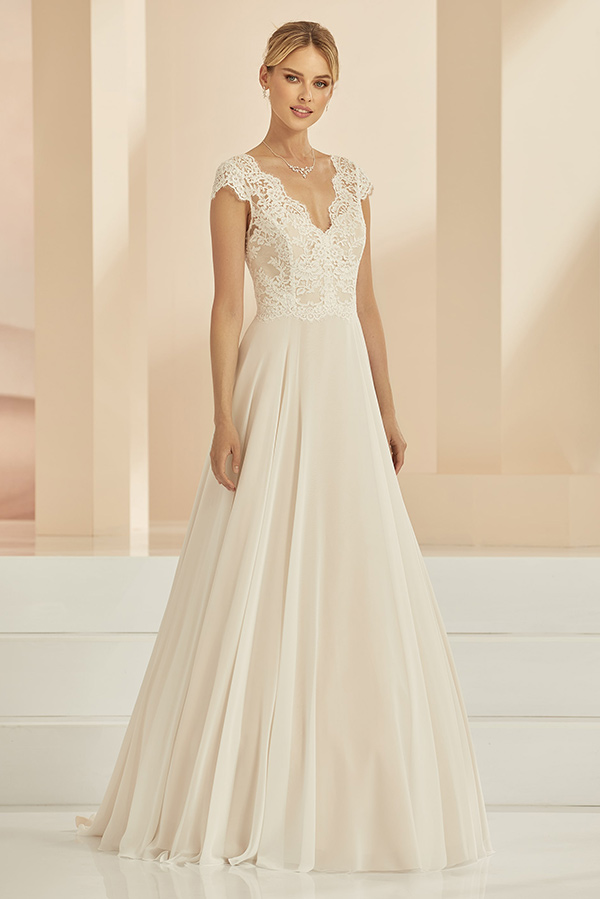 Junge Frau mit elegantem Lächeln trägt ein cremefarbenes Kleid mit Spitzendetails