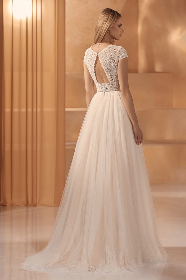 Junge Frau mit langen blonden Haaren trägt ein cremefarbenes Kleid mit Rückenausschnitt