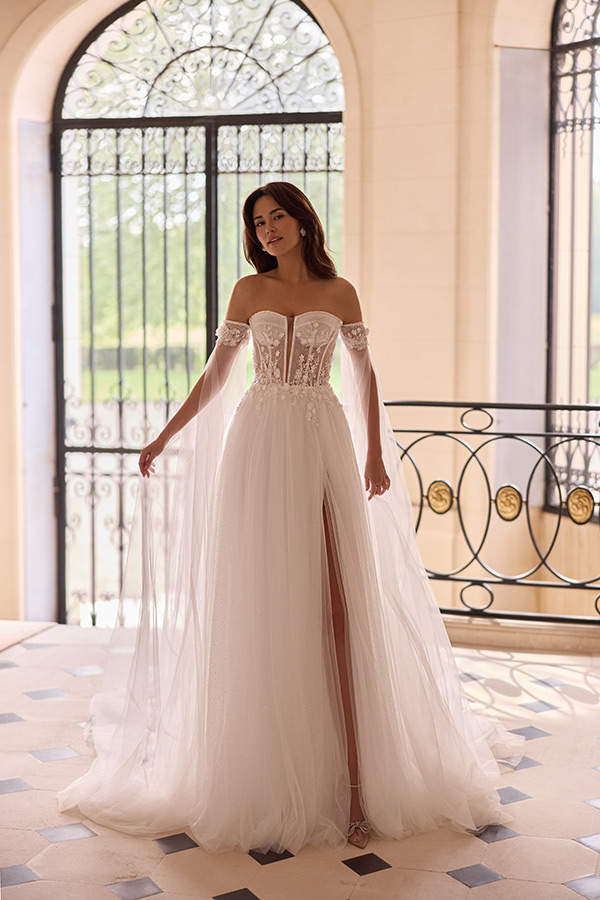 Eine junge Frau mit entspanntem Gesichtsausdruck trägt ein elegantes weißes Brautkleid