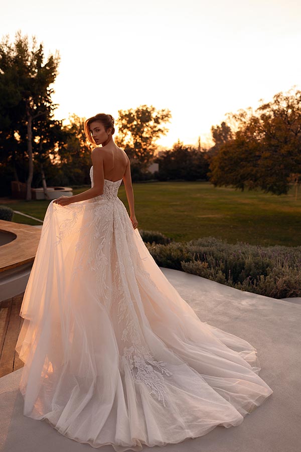 Eine Frau mit elegantem Gesichtsausdruck trägt ein weißes Spitzenkleid im Abendlicht