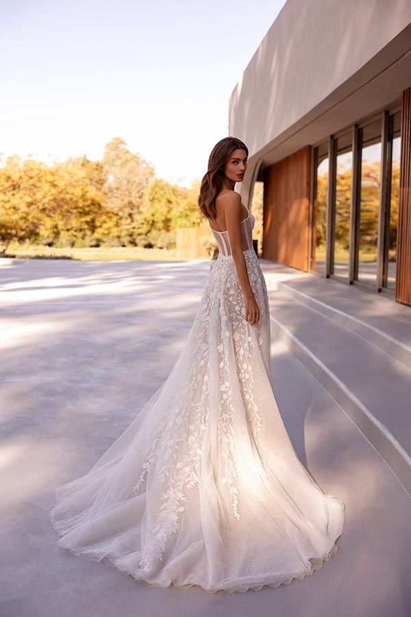 Eine junge Frau im weißen Spitzenkleid blickt lächelnd über die Schulter