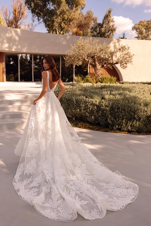 Eine lächelnde Frau trägt ein elegantes weißes Kleid mit Spitzenmuster im Garten