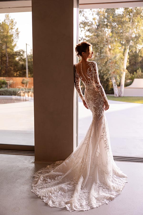 Frau in elegantem Spitzenkleid mit Schleppe blickt verträumt nach draußen