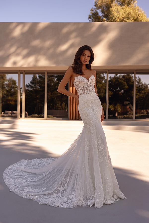 Junge Frau mit elegantem weißen Brautkleid und Spitzen, schaut ruhig in die Kamera