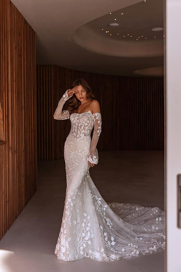 Eine junge Frau mit sanftem Blick trägt ein elegantes weißes Spitzen-Brautkleid