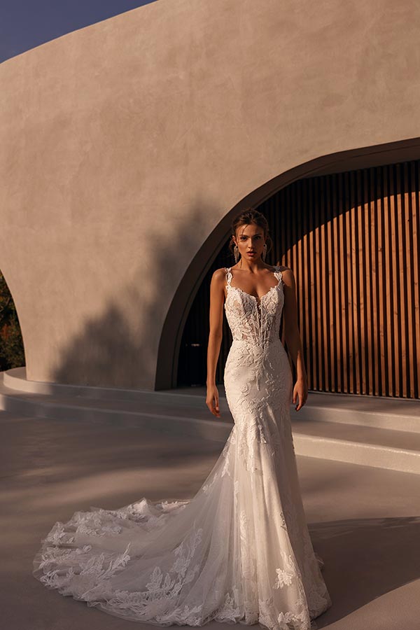 Eine junge Frau mit ernstem Ausdruck trägt ein elegantes, weißes Spitzenkleid