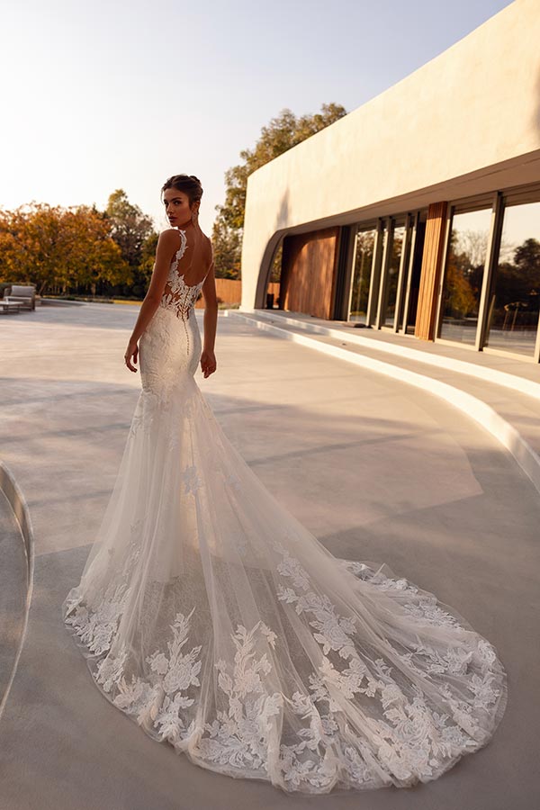 Eine junge Frau im eleganten weißen Brautkleid blickt ernst über die Schulter zurück