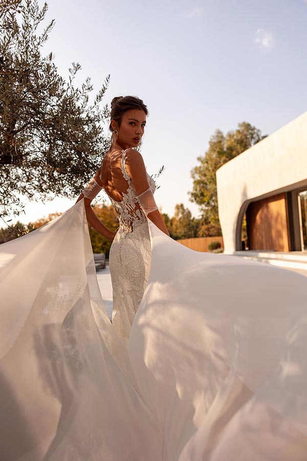 Eine Frau im eleganten Spitzenkleid mit offenem Rücken schaut verträumt zurück