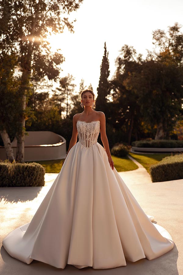 Eine elegant gekleidete Frau im weißen Brautkleid mit Spitzencorsage im Garten