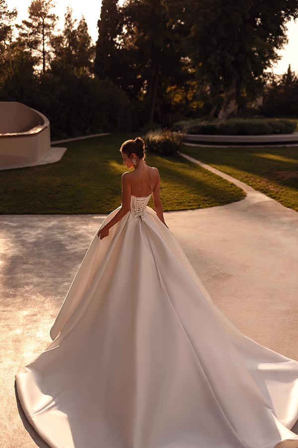 Eine Frau in einem eleganten weißen Brautkleid steht mit dem Rücken zur Kamera