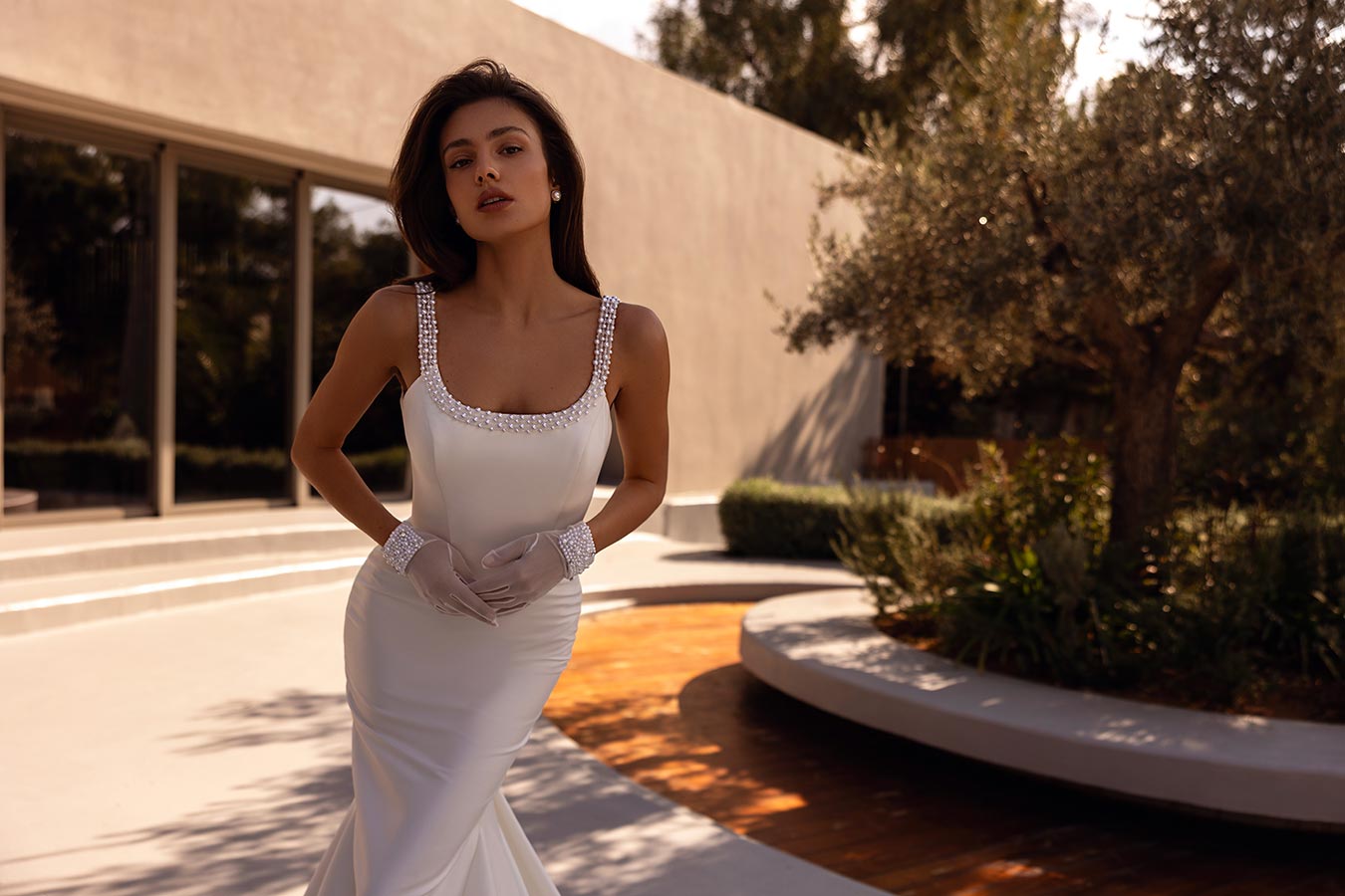 Eine elegant gekleidete Frau mit sinnlichem Blick trägt ein weißes Perlenkleid