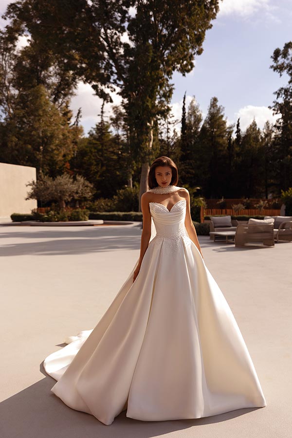 Eine junge Frau im eleganten weißen Brautkleid mit herzförmigem Ausschnitt draußen