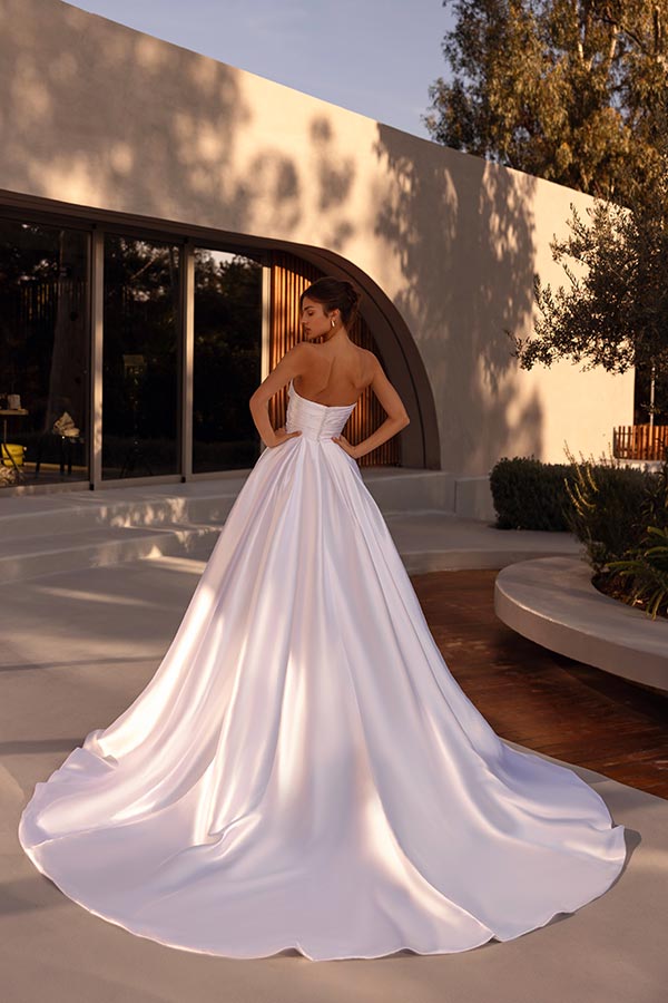 Eine elegant gekleidete Frau mit weißem, glänzendem Kleid schaut über ihre Schulter