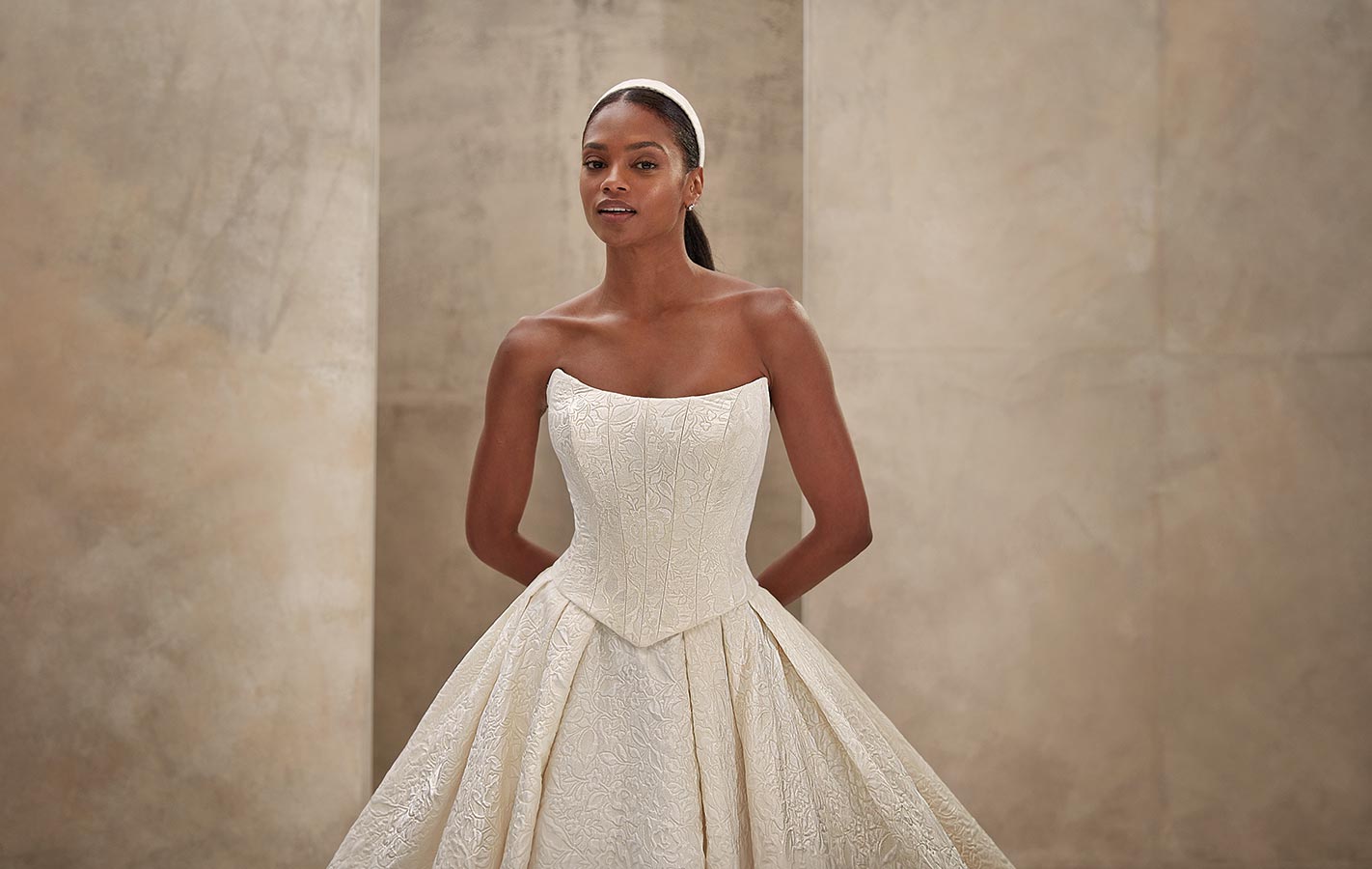 Eine lächelnde Frau mit dunkler Haut trägt ein elegantes weißes Brautkleid