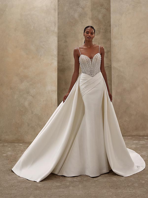 Elegante Frau in cremefarbenem Brautkleid mit funkelndem Oberteil und ruhigem Blick