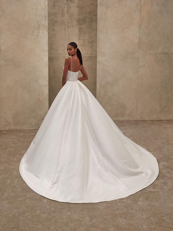 Eine elegant gekleidete Frau in weißem Brautkleid blickt über die Schulter