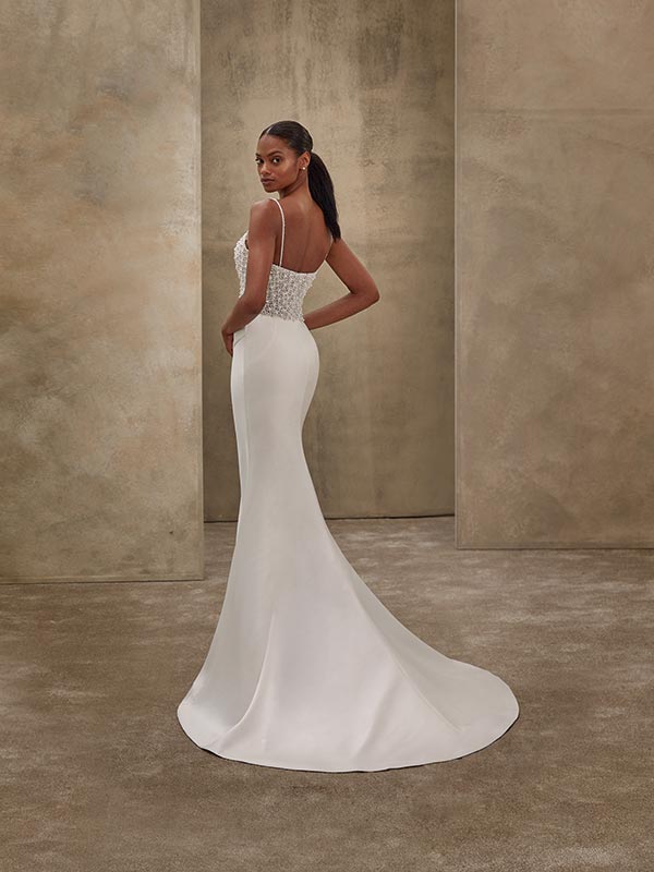 Eine elegant gekleidete Frau im weißen Brautkleid blickt ernst über die Schulter