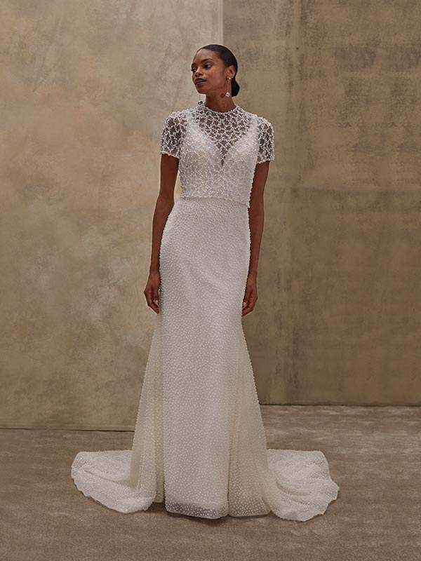 Eine elegant posierende Frau mit dunkler Haut trägt ein aufwendig besticktes Brautkleid