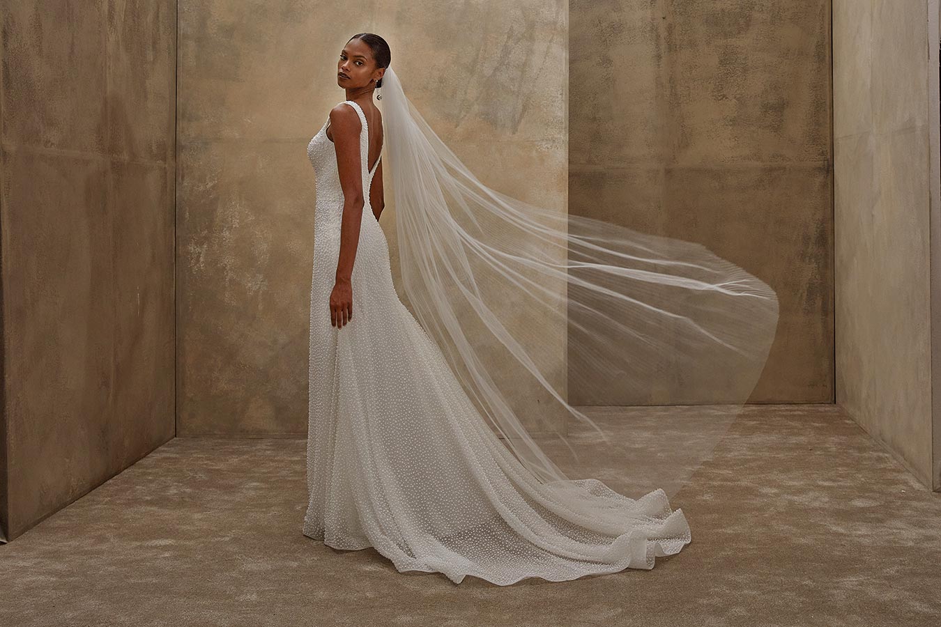 Eine Frau in einem weißen Brautkleid mit langem Schleier schaut ernst zur Seite