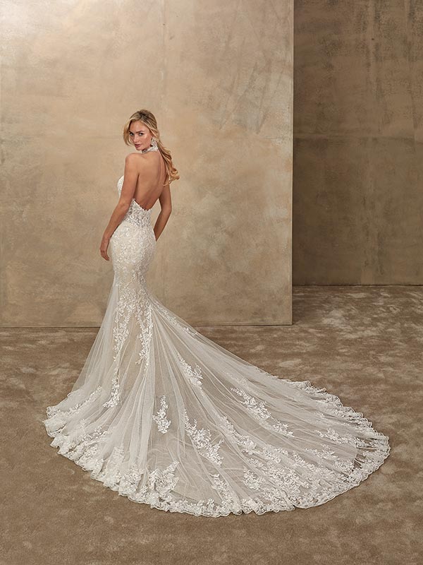 Eine blonde Frau blickt elegant über die Schulter und trägt ein weißes Spitzenkleid