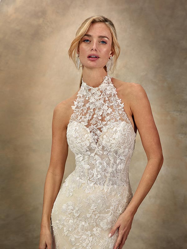 Blonde Frau mit neutralem Blick trägt elegantes weißes Spitzenkleid mit Blumenmuster