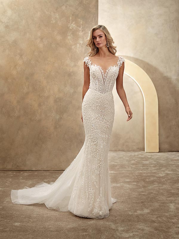 Eine elegante blonde Frau mit sanftem Lächeln in cremefarbenem Spitzenbrautkleid