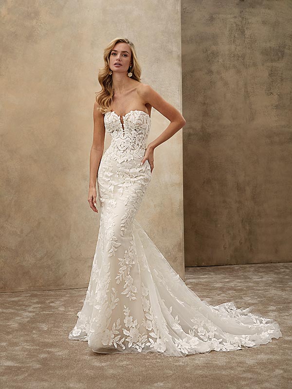 Eine blonde Frau mit ernstem Blick trägt ein elegantes, weißes Spitzenkleid