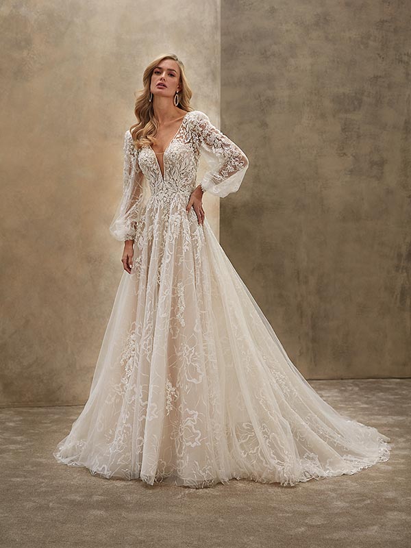 Eine blonde Frau mit sanftem Gesichtsausdruck trägt ein elegantes cremefarbenes Spitzenkleid