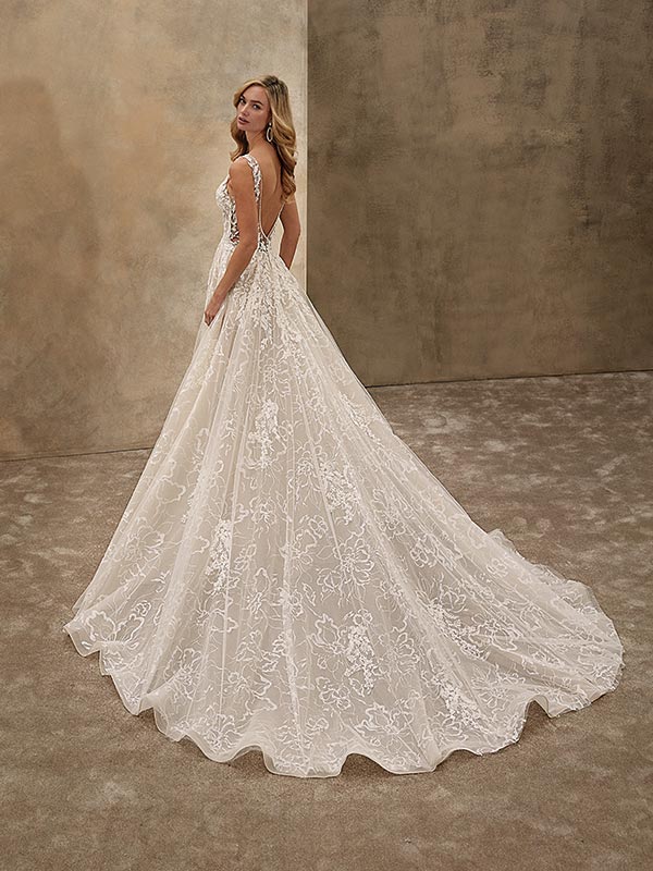 Eine blonde Frau im eleganten Spitzenkleid blickt lächelnd über die Schulter zurück