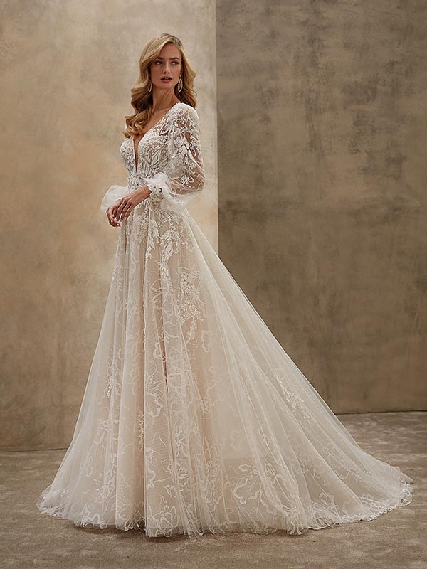 Eine blonde Frau lächelt sanft in einem eleganten weißen Spitzenbrautkleid