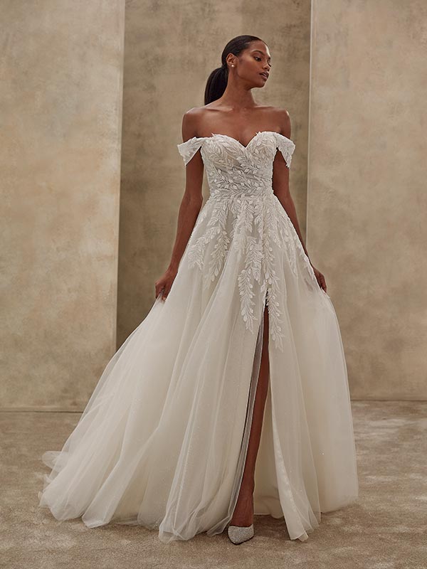 Elegante Frau in weißem Brautkleid mit floraler Spitze und stolzer Pose