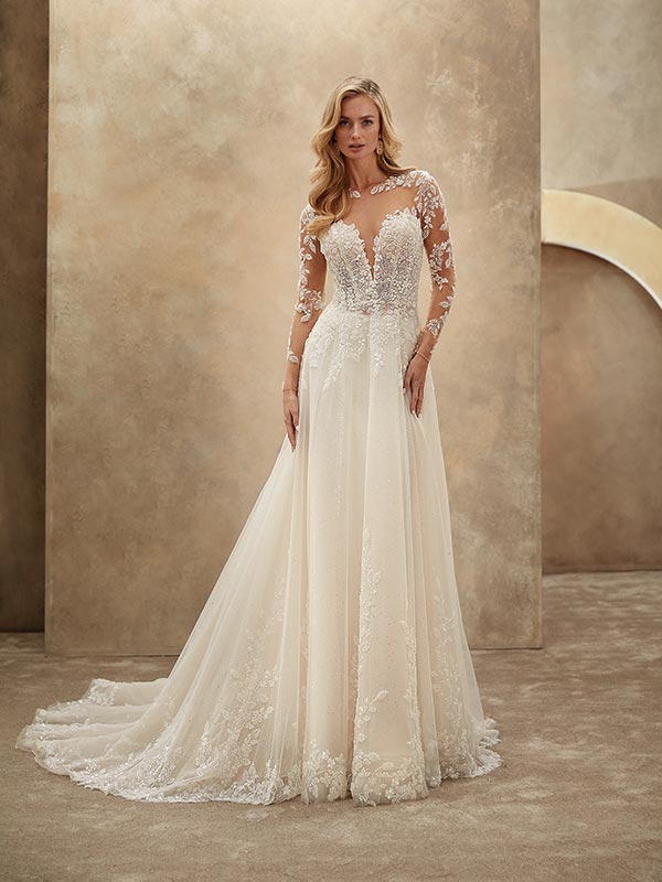 Eine blonde Frau mit elegantem Blick trägt ein cremefarbenes Spitzenhochzeitskleid