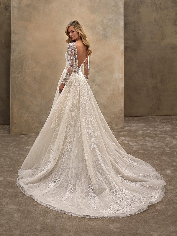 Blonde Frau lächelt sanft in elegantem Spitzenkleid mit langem, transparentem Rücken