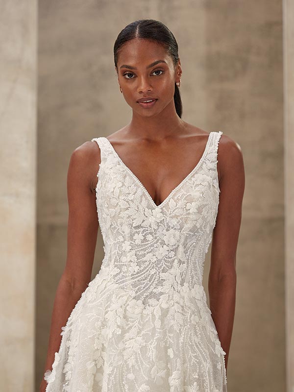 Eine Frau mit glatter dunkler Haut und ernster Miene trägt ein weißes Spitzenkleid