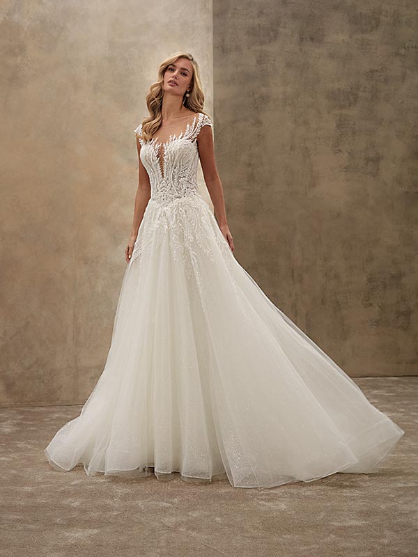 Eine blonde Frau im eleganten weißen Brautkleid blickt verträumt und steht ruhig