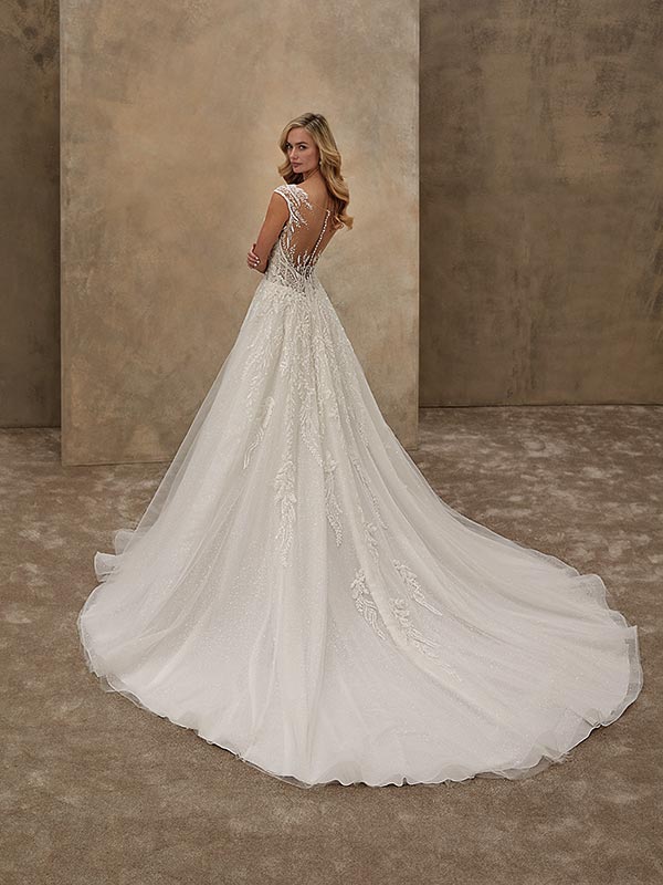 Eine lächelnde Frau mit langen blonden Haaren trägt ein edles weißes Brautkleid