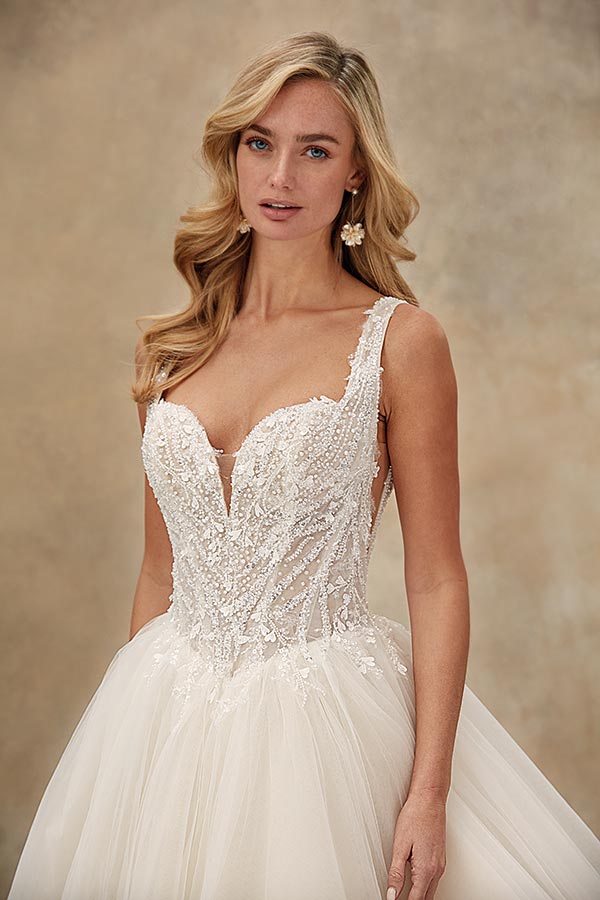 Junge Frau mit langen blonden Haaren und sanftem Blick im detailreichen Brautkleid