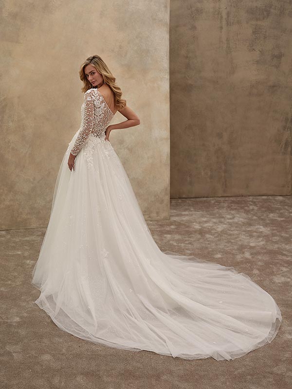 Eine blonde Frau im eleganten weißen Brautkleid mit Spitze blickt über die Schulter