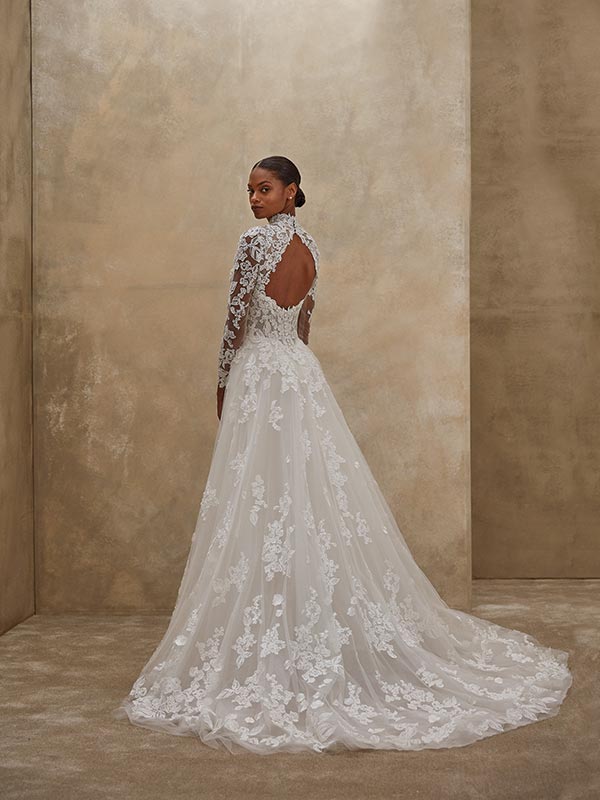 Eine Frau im eleganten weißen Spitzenkleid blickt ruhig über die Schulter